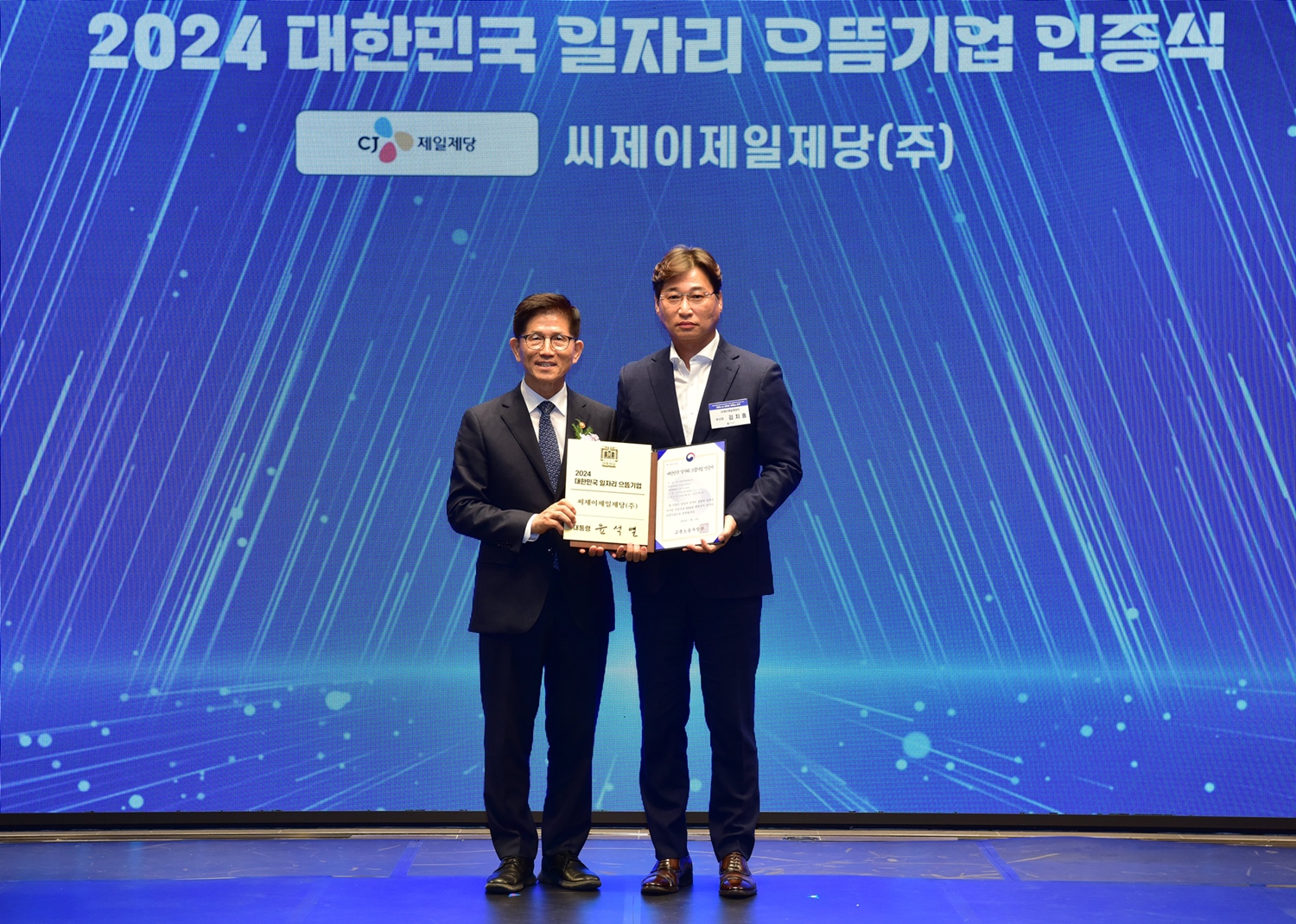 CJ제일제당 노사협력담당 김치홍 상무(우)와 고용노동부 김문수 장관(좌)이 일자리 으뜸기업 인증식에서 기념 촬영을 하고있다