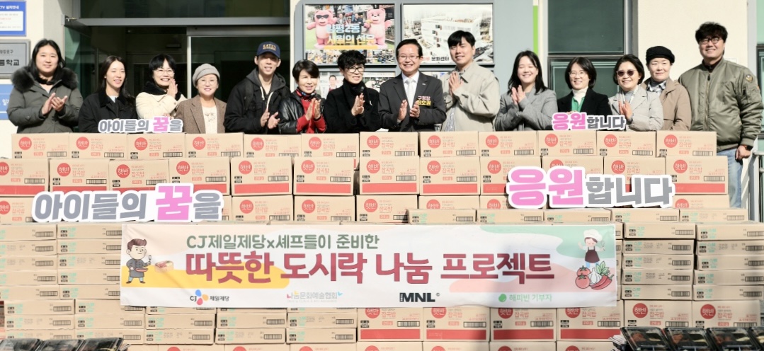 '셰프의 나눔 도시락' 행사를 진행한 사진. CJ제일제당 셰프들이 준비한 따뜻한 도시락 나눔 프로젝트 라는 현수막을 앞에 걸고 CJ제일제당 상품 박스들과 참여자들이 사진을 찍고 있다.