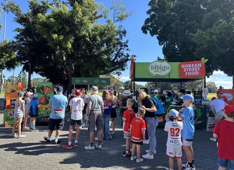 Australian consumers line up at the sampling booth outside the stadium to try bibigo products