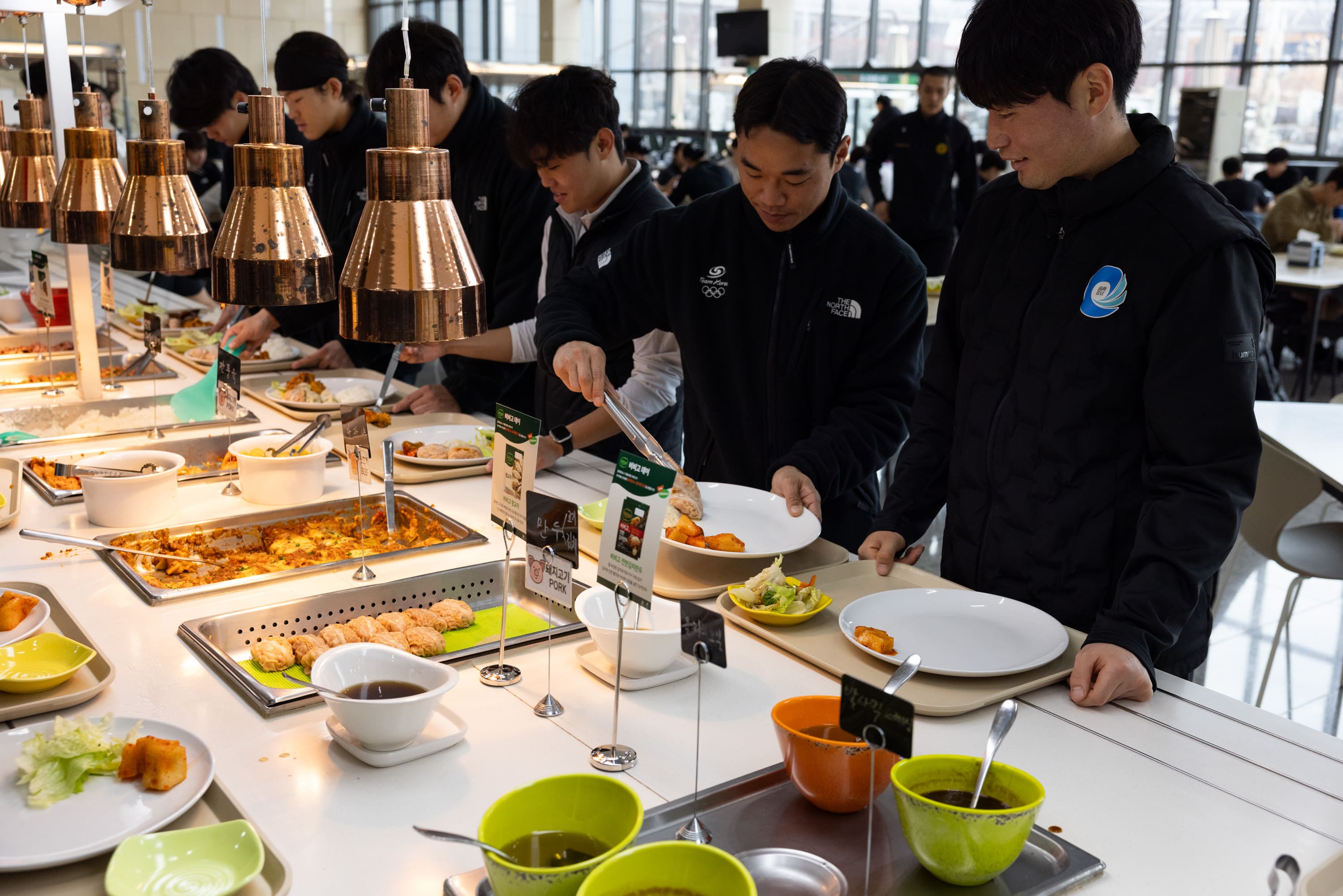 훈련을 마치고 식당에 방문한 선수들이 비비고 왕교자를 접시에 담고 있다