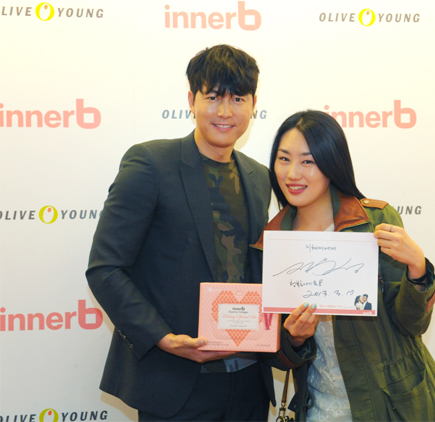 이너비 모델 정우성과 그에게 싸인을 받은 팬이 나란히 서서 이너비 제품을 들고 미소짓고 있다.
