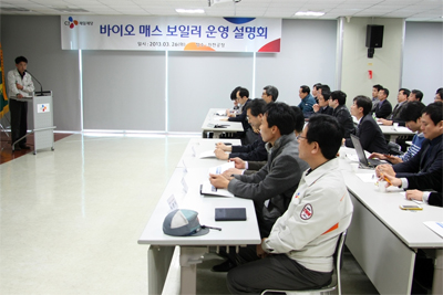 바이오 매스 보일러 운영 설명회에서 한 명의 강연자가 설명을 하고 있으며, 많은 참가자들이 의자에 앉아 경청을 하고 있다.